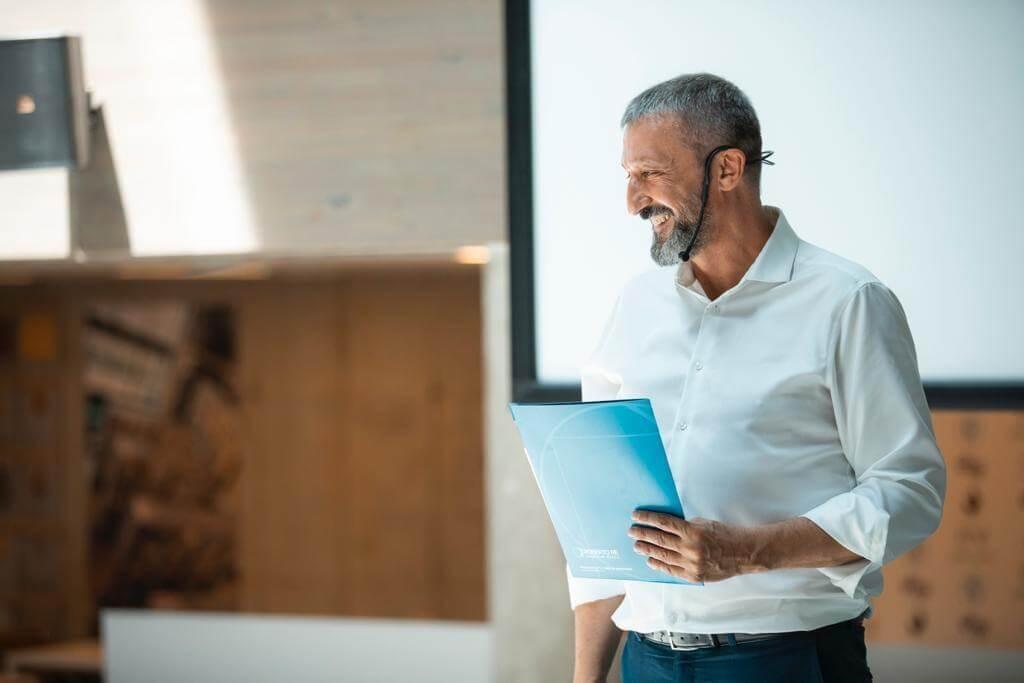 Stefano Denna sorridente che guarda i suoi alunni